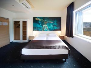 耶拿B&B Hotel Jena的一间卧室设有一张床和一个大窗户