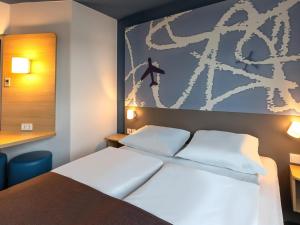 劳森豪森B&B HOTEL Frankfurt-Hahn Airport的一间设有一张床的客房,墙上挂着一幅画