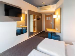 劳森豪森B&B HOTEL Frankfurt-Hahn Airport的配有一张床和一张书桌的酒店客房