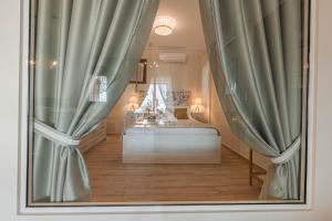 卡西罗彼卡多Paralio Astros Beachfront Suites的一间卧室配有床和带窗帘的窗户