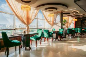 艾卜哈فندق إيفا إن的餐厅设有绿色的椅子和桌子以及窗户。