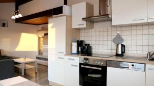 梅舍德Ferienhaus Henneseeblick - Lake - View - Terrace - Hils - Wood - WIFI的厨房配有白色橱柜和炉灶烤箱。