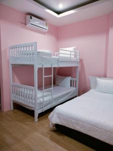 Suen PhraHana Villa Hatyai的粉红色墙壁的客房内设有两张双层床。