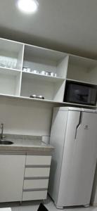 巴西利亚VISION Flat Particular Varanda Garagem Piscina Academia的白色的厨房配备了微波炉和冰箱。