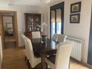 哈卡Modern & cosy Apartment in Jaca Pyrenees Spain的一间带木桌和白色椅子的用餐室