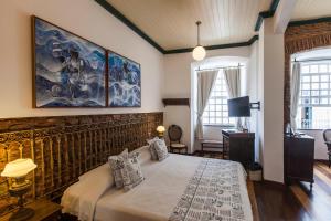 萨尔瓦多太阳神旅馆的卧室配有一张床,墙上挂有绘画作品
