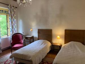 maison de campagne avec grand lac et park arboré的一间卧室配有两张床、一把椅子和一个吊灯。