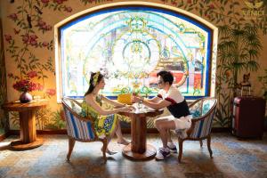 富国Venice Hotel Phu Quoc - Free Hon Thom Island Waterpark Cable Car & Sunset Town Tour的坐在餐厅桌子上的男女