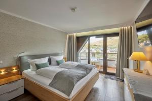 摩泽尔河畔的泽尔梅耶韦恩酒店的一间带大床的卧室和一个阳台