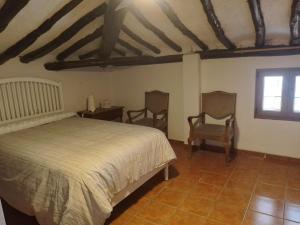 VillatuertaCasa Rural 643km的一间卧室配有一张床和两把椅子