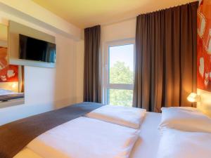 斯图加特B&B Hotel Stuttgart-Bad Cannstatt的酒店客房设有床和窗户。