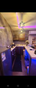欧普尔شالية منتجع ارض السعادة 1的厨房的天花板上配有紫色灯和柜台