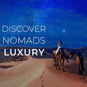 AdrouineNomads Luxury Camp Merzouga的一位晚上在沙漠骑骆驼的女人
