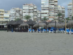 马拉加Apartamento Buen Dia airport Malaga- playa-Torremolinos的海滩上的一组椅子和遮阳伞