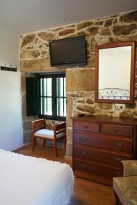 布埃乌Casa Videira - Hotel rural cerca del mar的一间卧室配有梳妆台和石墙上的电视