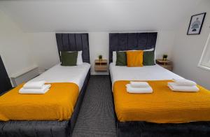 伦敦Woodford Hotel的配有两张带橙色和白色毛巾的床铺