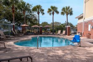 查尔斯顿Comfort Inn & Suites Patriots Point的一个带蓝椅和棕榈树的游泳池