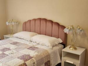 拉瓦尔Comfortable entire 3BDR Apt in Laval Montreal的一张带粉红色床头板的床和两张带台灯的桌子