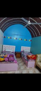 Najâ€˜ al MadÄbbNuba life Mostafa Guesthouse的蓝色墙壁客房的两张床