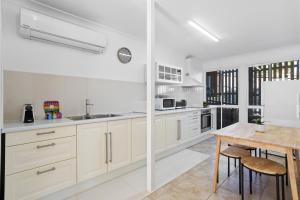 布里斯班Urban Apartment in the Heart of Paddington的厨房配有白色橱柜和木桌