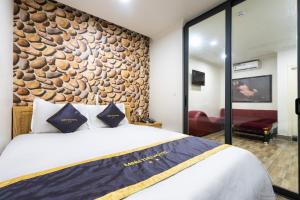 胡志明市MINH THƯ HOTEL的一间卧室设有一张大床和石墙