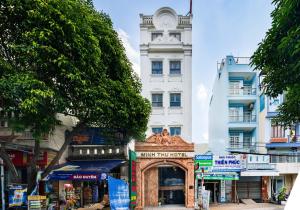 胡志明市MINH THƯ HOTEL的街道上一座白色的建筑,有钟楼