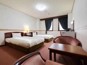 富山ecoHotel的酒店客房带两张床和一张桌子以及椅子。