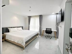 胡志明市Thinh Vuong Apartment IX的一间卧室配有一张床、一张书桌和一台电视