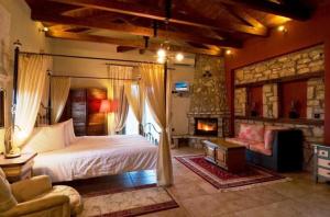 Kalyvia阿约利德斯酒店的一间卧室设有一张大床和一个壁炉