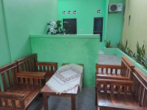 班达楠榜OYO 93695 Guest House Riharti Syariah的两把木长椅,位于带绿色墙壁的房间