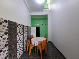 班达楠榜OYO 93695 Guest House Riharti Syariah的绿墙客房内的桌椅