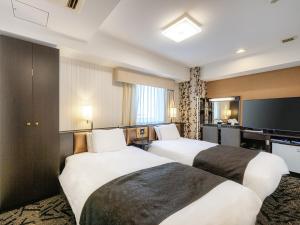 燕市APA Hotel Niigata Tsubame-Sanjo Ekimae的酒店客房配有两张床和一张书桌