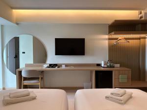 曼谷Jace hotel的一间卧室配有一张桌子和一台墙上的电视。