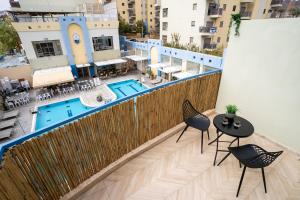 埃拉特Almogim Suites Eilat的公寓的阳台配有桌椅和游泳池。
