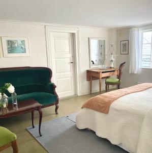 SkudeneshavnReinertsenhuset的一间卧室配有一张床、一张绿色沙发和一张书桌