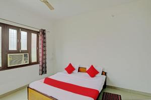 瓦拉纳西Super OYO Flagship Shivansh Paying Guest House的一间卧室配有一张带红色枕头的床和一扇窗户