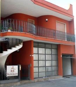 Sogliano Cavour圣塔卢西亚B&B酒店的一座红色的建筑,旁边设有阳台