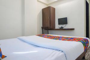 浦那FabHotel Gokul Lodge的一间卧室配有一张床,墙上配有电视