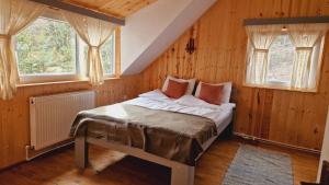 CiceuVén Fenyő Kunyhó的木墙和窗户的客房内的一张床位