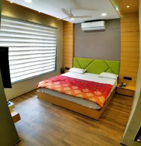 伯杰默里Hotel Rajlaxmi的一间卧室配有一张带绿色床头板的床和窗户
