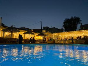 提诺斯Aeolos Bay Tinos的游泳池在晚上设有一组桌子和遮阳伞