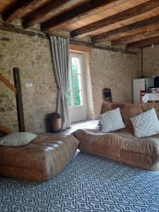 蒙蒂尼亚克Le Chai, gîte de charme avec piscine的客厅配有真皮沙发和窗户