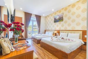 大叻Villa Hoa Ly Đà Lạt的一间卧室配有两张床和一张鲜花桌
