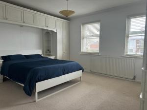 埃文河畔斯特拉特福Stratford upon Avon: 2 bed town centre apartment, parking for one car的一间卧室配有一张带蓝色床单的床和两个窗户。