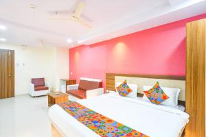 海得拉巴FabHotel Prime SYN Grand的一间卧室设有一张大床和粉红色的墙壁