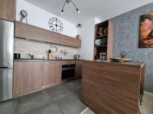 罗兹Q Apart Gold-3 Pokoje Manufaktura Garaż Netflix Klimatyzacja, FV,的厨房配有木制橱柜和不锈钢冰箱。