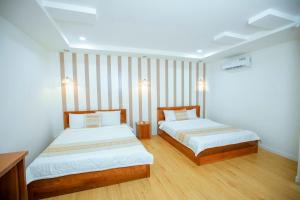金瓯khách sạn Quốc Tế的一间卧室设有两张床,铺有木地板