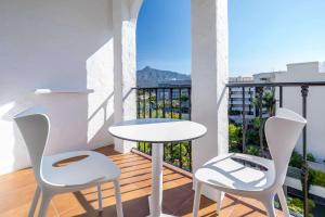 马贝拉Occidental Puerto Banús的阳台配有白色的桌子和两把椅子