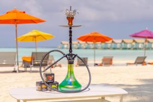南马累环礁Hard Rock Hotel Maldives的海滩上带遮阳伞的桌子上的一瓶