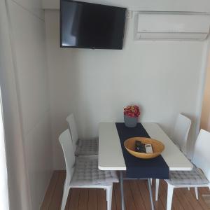 耶泽拉Mobile home Comfort Jezera Murter的餐桌、白色椅子和墙上的电视